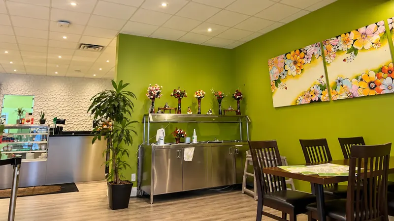 Tables beside the green feature wall and floral artwork at The Bombay Grill Milton